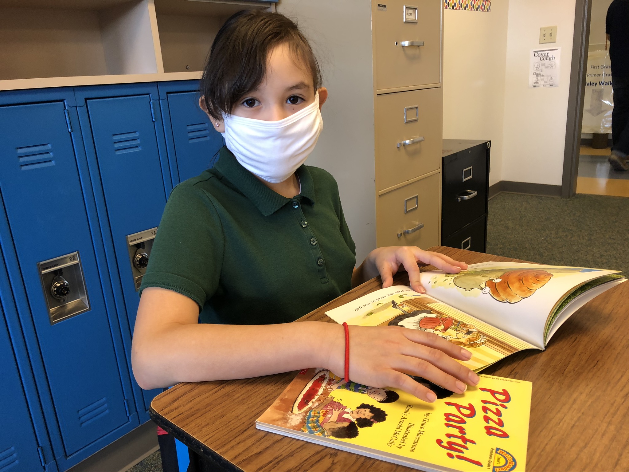 Girl reading a book with a mask on